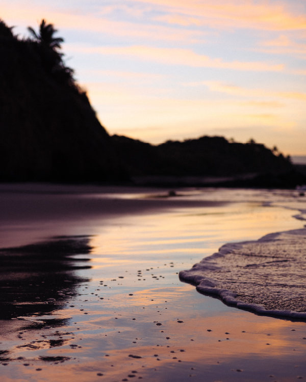 Ein malerischer Blick bei Sonnenuntergang auf die Küste und das Wasser an einem Strand