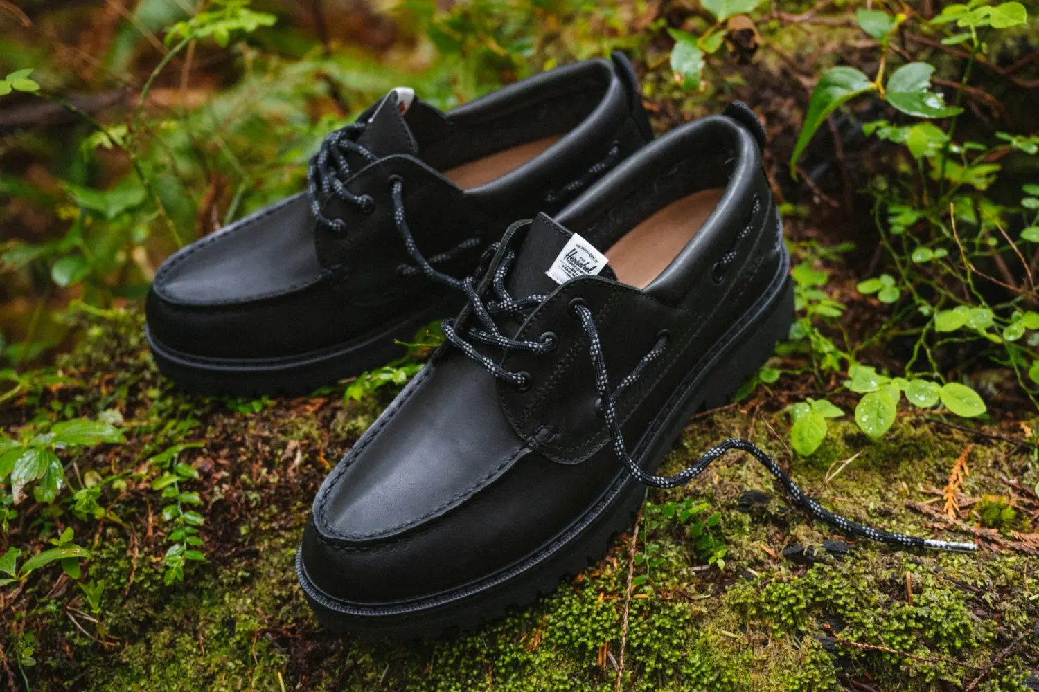The Sperry x Herschel Authentic Original 3-Eye Lug Shoe in Black on mossy ground