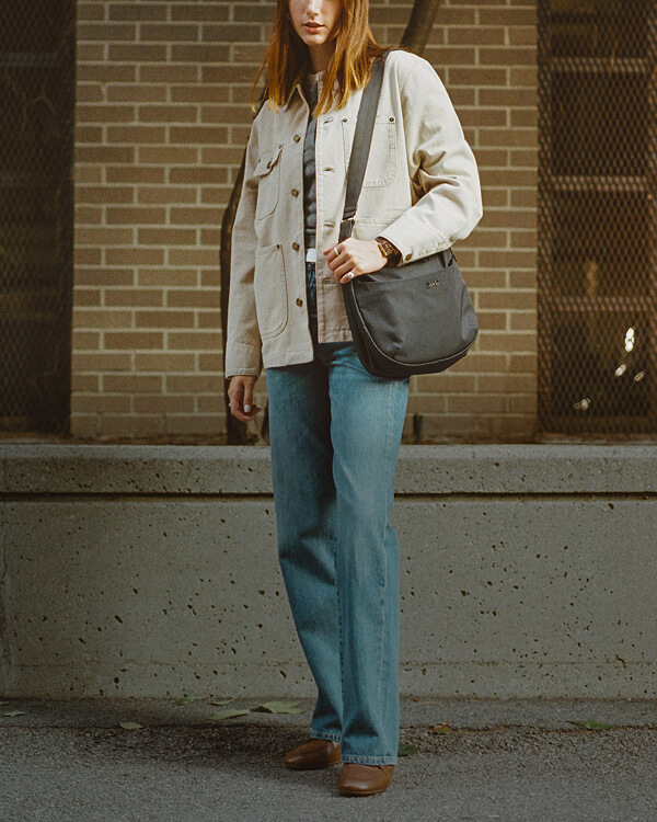 a well dressed woman holds a yara shoulder bag in black over her left shoulder.